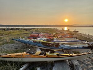 Kayaks on the beach with sun setting behind